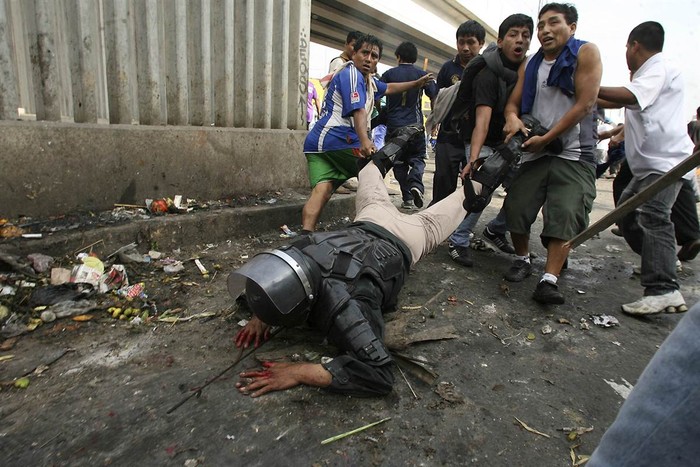 Người biểu tình kéo lê một cảnh sát chống bạo động rơi xuống ngựa sau khi bị công nhân ném đá ở Lima, Peru hôm 25/10. Đụng độ giữa các công nhân ngành bán sỉ và cảnh sát đã khiến 2 người chết và hơn 100 người bị thương.